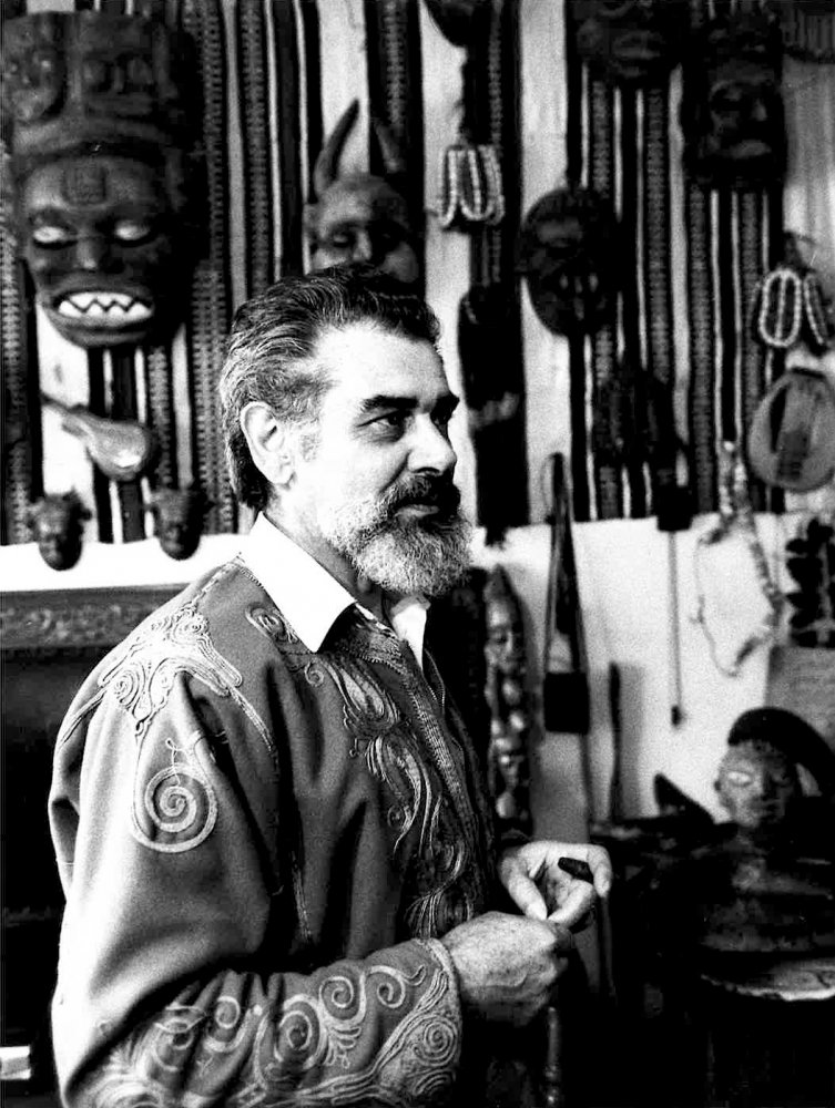 Riccardo Micheletti nel suo studio, di fronte a alcuni oggetti raccolti in Nigeria. Fotografia del 1974.